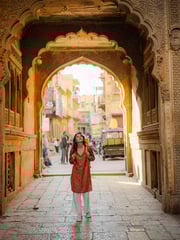 Cheerful woman exploring ornate haveli in Jaisalmer old town during...