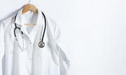Doctor's white coat with stethoscope on hanger over white background...