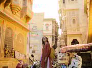 Cheerful woman walking on crowded street in old town of Jaisalmer,...