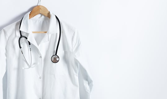 Doctor's white coat with stethoscope on hanger over white background...