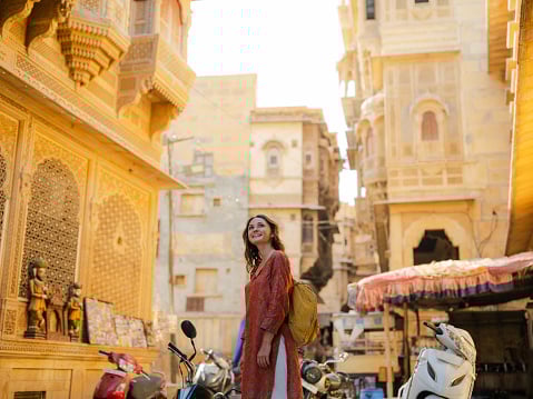 Cheerful woman walking on crowded street in old town of Jaisalmer,...